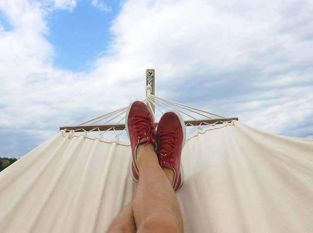 feet in hammock to represent doing nothing and relaxing to have a more balanced life