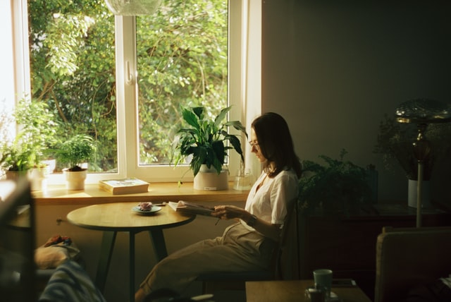 woman sitting at a table reading to represent an independent woman