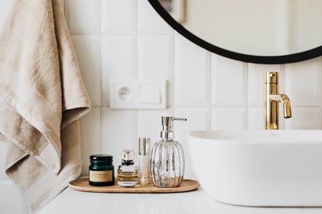 bathroom counter with soap and perfume next to a sink