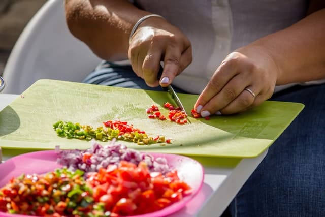 close up of hands chopping vegetables into small pieces