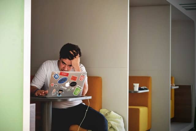 man in booth using laptop with stickers on it