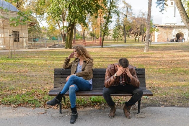 two people on bench facing away from each other