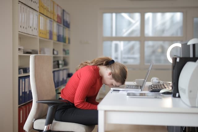 girl sitting at desk with head down on laptop