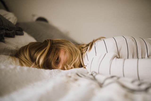 girl laying face down on bed looking at camera