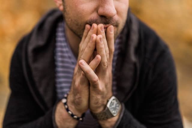 close up of man with hands at his mouth