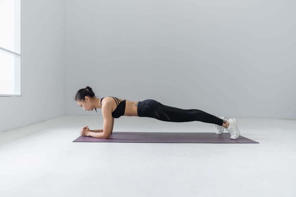 girl doing a plank on yoga mat in an empty room