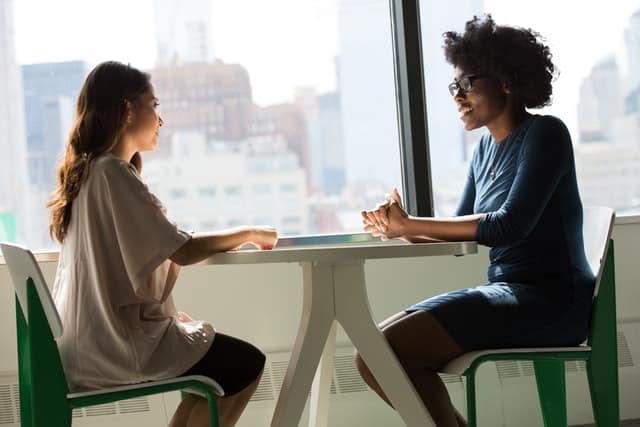 2 women sitting at a table negotiating for a better job